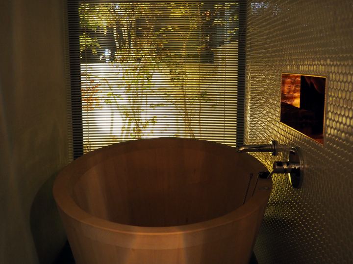 Round cedar soaking tub in a dark tiled bathroom