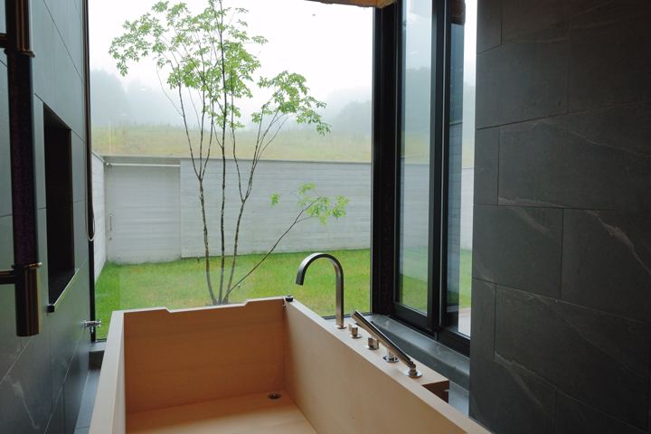 Wooden soaking tub beside a garden window
